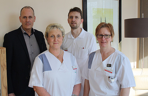 Ein wohnliches Umfeld für unheilbar erkrankte Patienten: Pflegedirektor Wilfried Schlotmann (hinten li.), Stützpunktkoordinator Dieter Rolfes (hinten re.) und Kolleginnen aus der Stationspflege präsentieren das neue Wohnzimmer der Palliativstation des